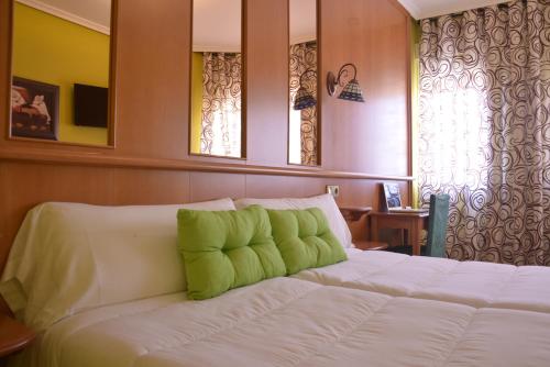 a bedroom with a white bed with green pillows on it at Hotel Aro'S in Casas Ibáñez