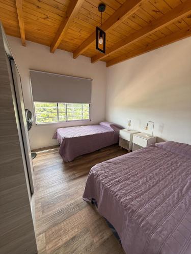 a bedroom with two beds and a window at Las Pirquitas Villa Giardino in Huerta Grande