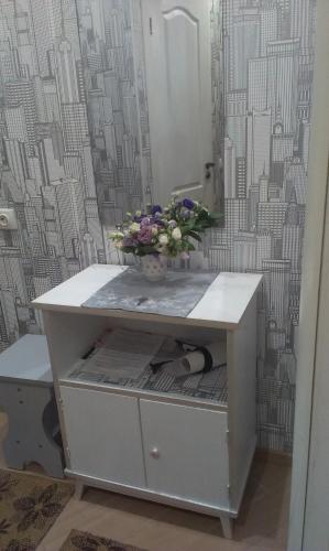 a vase of flowers sitting on top of a dresser at Apartment Chernovola 7A in Shostka