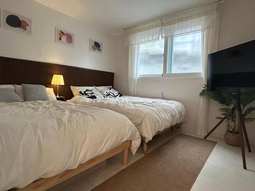 a bedroom with two beds and a flat screen tv at Hill-house in Samgong