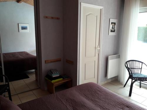 ein Zimmer mit einem Schlafzimmer mit Tür und Stuhl in der Unterkunft LesFrugères in Boutiers-Saint-Trojan