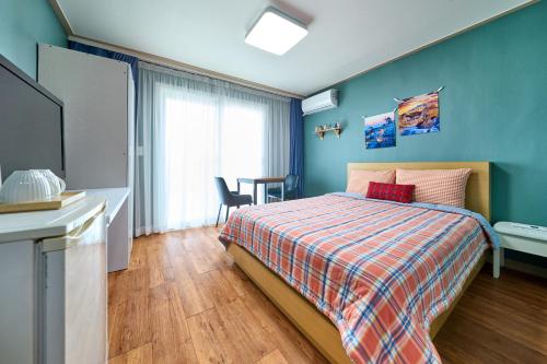 a bedroom with a bed and a desk and a tv at Naksanstay in Yangyang