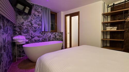 a purple bedroom with a tub and a bed at Corte d'Arnosto - Casa Virginia in Fuipiano Valle Imagna