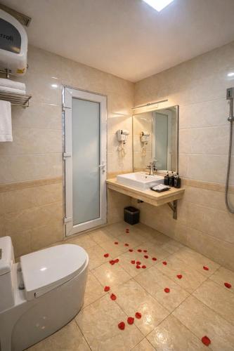 a bathroom with a toilet and a sink with red flowers on the floor at khách sạn Aloha in Hanoi