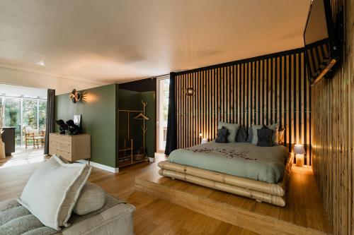 a bedroom with a large bed and a couch at L'orée du bois aux portes de Montauban in Albias