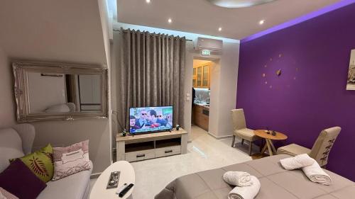 a living room with purple walls and a television at Aggelos Room 3 in Volos