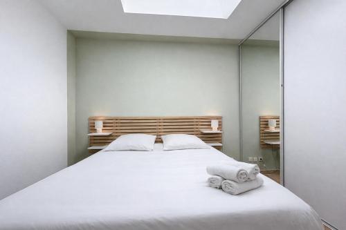 a bedroom with a large white bed and a mirror at Les Colonnes - Appartement en duplex - Wifi in Narbonne
