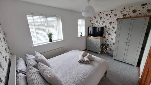 a bedroom with a bed with pillows and a television at Cosy Manorfield Holiday Home in Kent