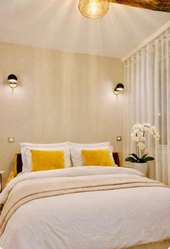 a bedroom with a large white bed with yellow pillows at Studio cosy avec parking près de Paris Expo Porte de Versailles in Vanves