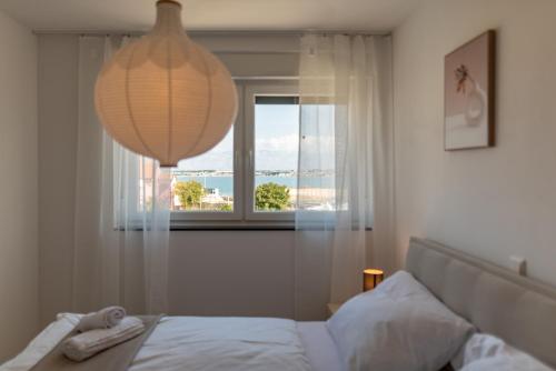 a bedroom with a bed with a chandelier and a window at Villa Mare e Monti in Nin