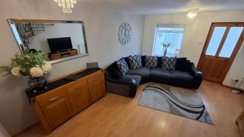 a living room with a black leather couch and a mirror at Cosy Manorfield Holiday Home in Kent