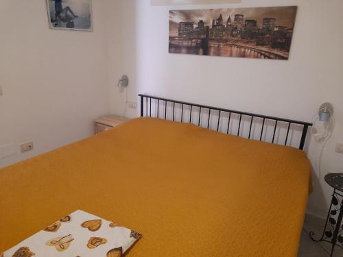a yellow bed in a bedroom with a picture on the wall at Casafreccia in Carloforte