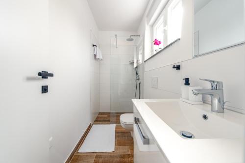 a white bathroom with a sink and a toilet at Villa Mare e Monti in Nin