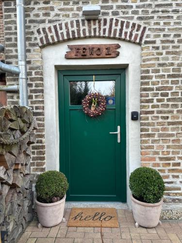 a green door on a brick building with two plants at Seeidyll an der Wublitz in Werder