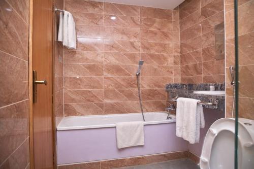 a bathroom with a tub and a toilet and a sink at Royalbirds Hotel & Towers in Akure