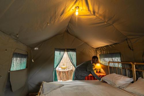 a woman is making a bed in a tent at Bunduz Mara in Sekenani