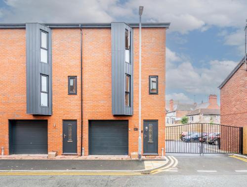 a brick building with two garage doors on a street at Exclusive New City Center Designer Mews Home in Chester