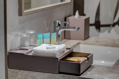 ein Waschbecken im Badezimmer mit einer Packung Handtücher in der Unterkunft Kingsgate Hotel Clock Tower in Dubai