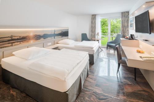 ein Hotelzimmer mit zwei Betten und einem Schreibtisch in der Unterkunft Hotel Heidehof garni in Büdelsdorf