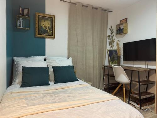 a bedroom with a bed with a desk and a television at Beau studio proche gare in Gagny