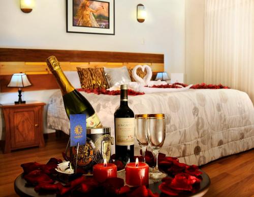 Habitación con 1 cama con 2 botellas de vino y copas en Hostal Ameron en Juliaca
