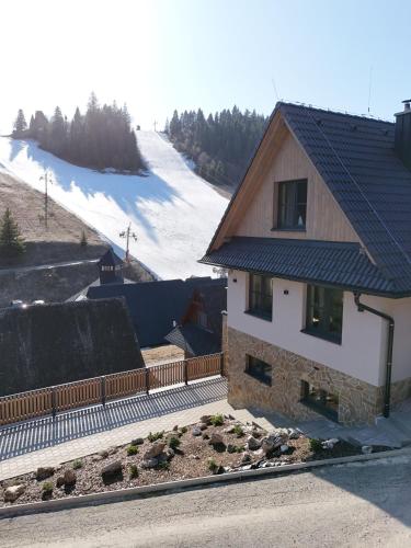 a house with a fence next to a snow covered slope at Chata Barvinok in Litmanová