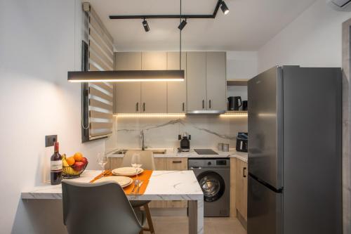 a kitchen with a table and a stainless steel refrigerator at Kallithea living in Koskinou