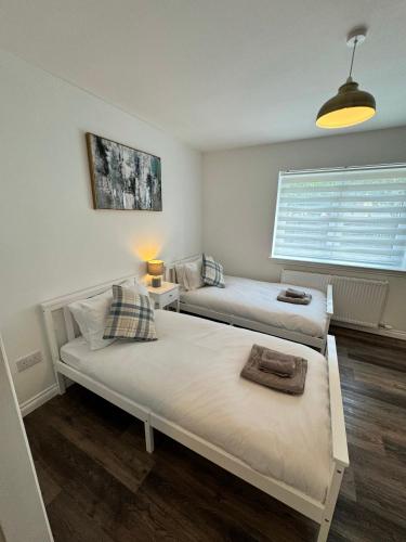 two beds in a room with a window at Inchmoan Apartment in Bonhill