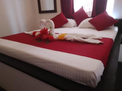 a bed with a red and white comforter at George Bungloaw in Henegama