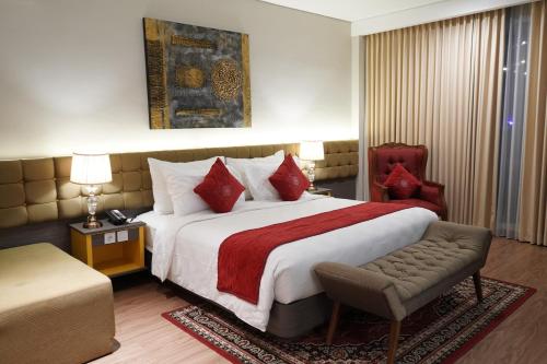 a hotel room with a large bed and a chair at Ramada by Wyndham Yogyakarta in Yogyakarta