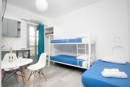 a bedroom with two bunk beds and a table and chairs at Depis suites naxos in Naxos Chora