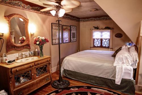 a bedroom with a bed and a sink and a mirror at The Queen, A Victorian Bed & Breakfast in Bellefonte