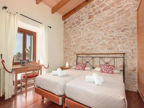 a bedroom with two beds and a stone wall at S'hort d'en Bonet in Santanyi
