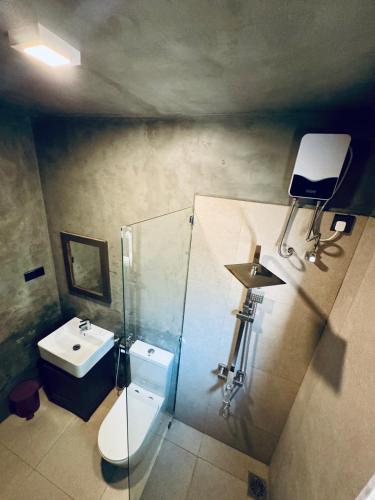 a bathroom with a sink and a toilet and a chair at The Dutch Station Hotel in Ambalangoda