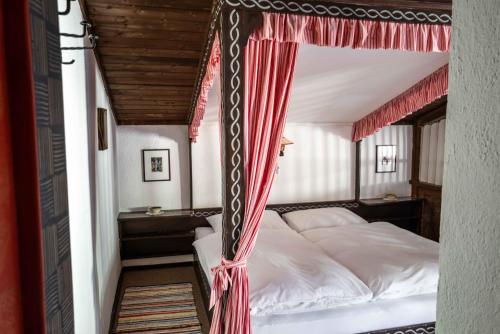 a bedroom with a canopy bed with red curtains at Berghotel Blaickner's Sonnalm in Zell am See