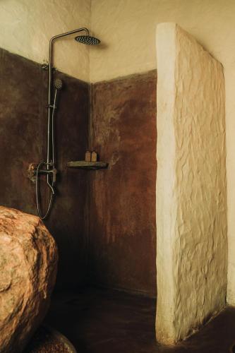 eine Dusche in einem Badezimmer mit einer Steinwand in der Unterkunft Arawe Retreat in Ella