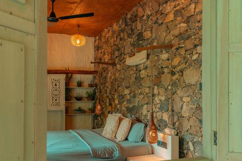 ein Schlafzimmer mit einer Steinwand und einem Bett in der Unterkunft Arawe Retreat in Ella