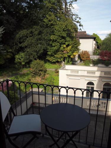 a table and chairs on a balcony with a white house at Boutique Hotel La Rinascente in Locarno