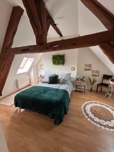 a bedroom with a large bed with a green blanket at Gîte de l horloge in Déols
