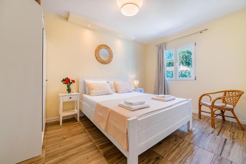 a bedroom with a white bed and a chair at Relaxing 2 bedroom apartment with Bay View and Parking in Prčanj