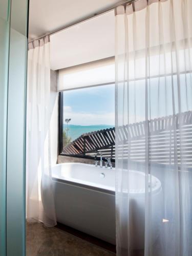 a bath tub in a bathroom with a window at The Now Hotel - SHA Extra Plus in Jomtien Beach