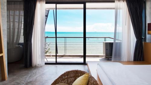 a bedroom with a large window with a view of the ocean at The Now Hotel - SHA Extra Plus in Jomtien Beach