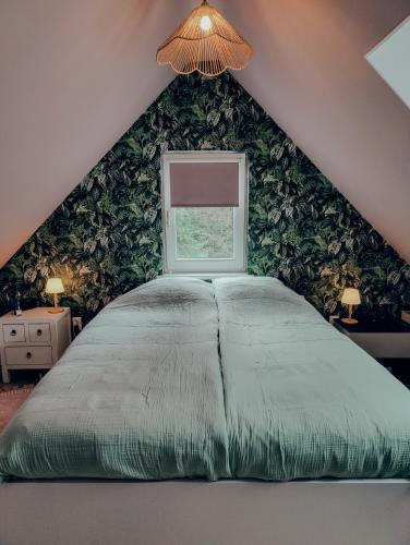 a bedroom with a large bed with a window at B&B 't Herfter Erf in Zwolle