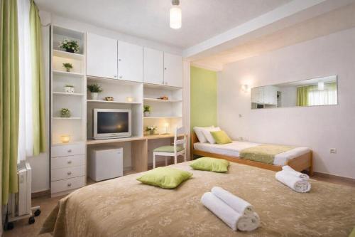 a bedroom with two beds and a desk and a television at Vila Kosta City Center Port in Ohrid