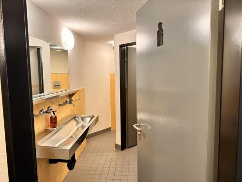 a bathroom with a sink and a mirror and a door at Abenteuer Turm in Braunwald