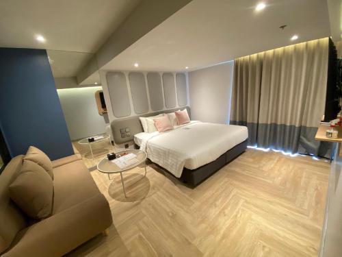 a bedroom with a bed and a couch at The Quarter Ladprao by UHG in Bangkok