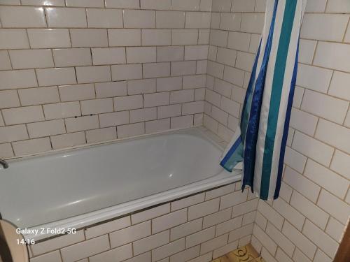 a white tiled shower with a blue shower curtain at Ubytovna Kadaň in Kadaň
