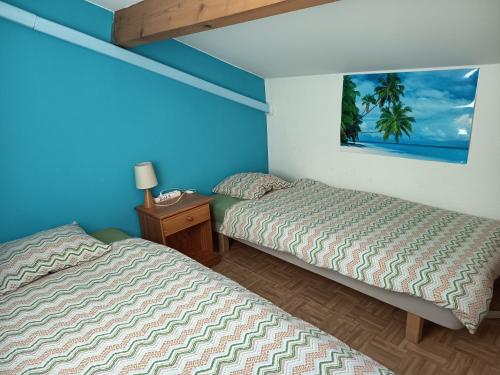 a bedroom with two beds and a night stand with a picture at Maison blanche in Calvisson