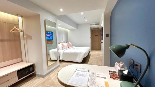 a room with a bed and a desk with a mirror at The Quarter Ladprao by UHG in Bangkok