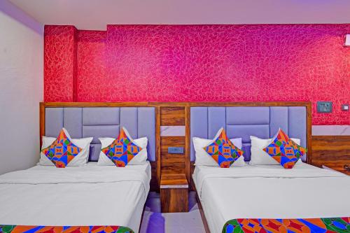 two beds in a room with pink walls at FabHotel SV Grand in Hyderabad